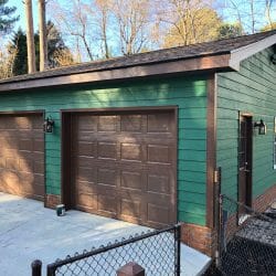 green & brown detached garage with brick trim