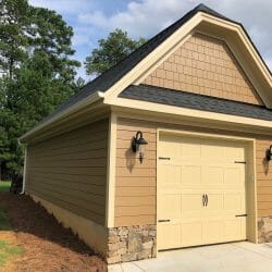 detached yellow vinyl garage with stone detail